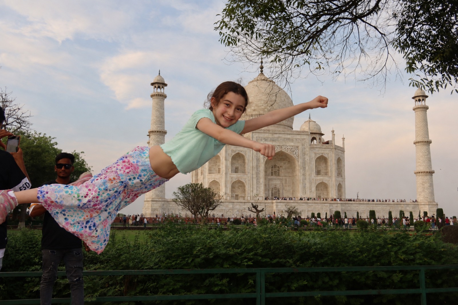 Eve flying through the air in a superhero pose in front of the Taj Mahal